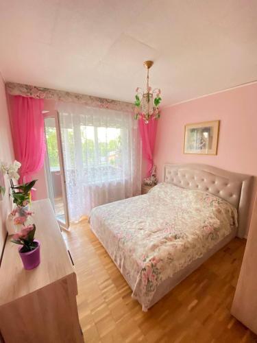 a bedroom with a bed and a window with pink curtains at Комната с лоджией у Татьяны in Jūrmala