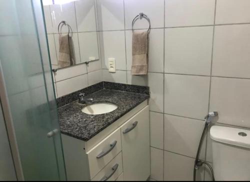 a bathroom with a sink and a mirror and a toilet at Apartamento em Mossoró in Mossoró