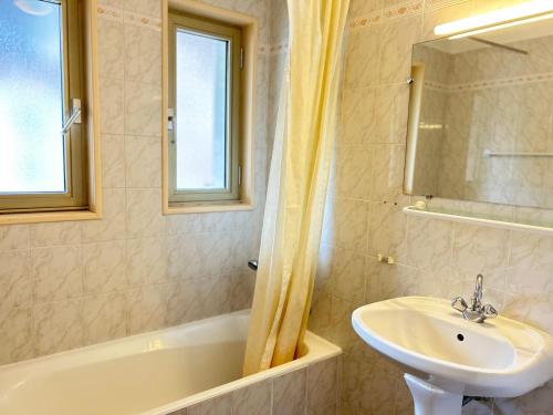 une salle de bain avec un lavabo, une baignoire et un miroir dans l'établissement Les Gets: Appartement central 2 ch, balcon, au pied des pistes - FR-1-623-132, aux Gets