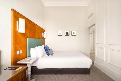 a hotel room with a white bed and a desk at voco Edinburgh - Royal Terrace by IHG in Edinburgh