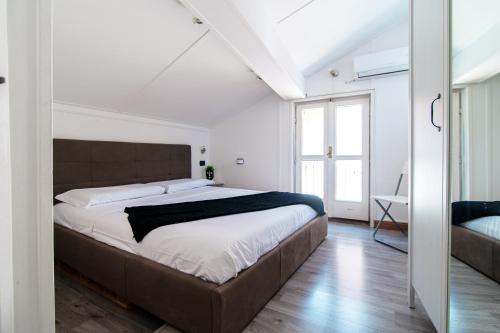 a bedroom with a large bed with white walls at JOIVY Al Duomo guest house in Como