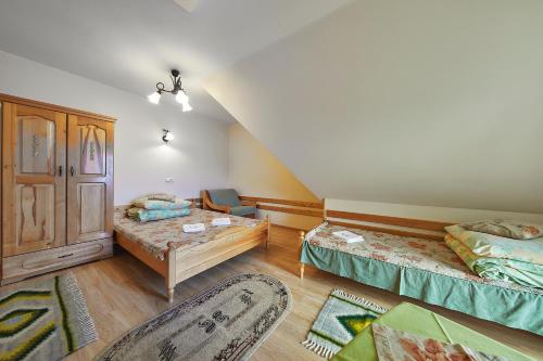 a attic room with two beds and a chair at Pokoje Cichy Kącik in Zakopane