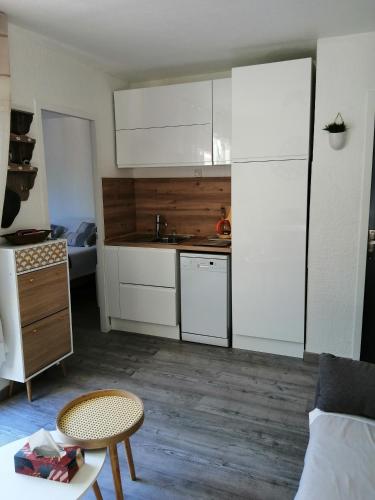 une petite cuisine avec des armoires blanches et une table dans l'établissement JOLIE APPARTEMENT A LOUER DANS LA PINEDE A 5MN A PIED DE LA PLAGE, à Argelès-sur-Mer
