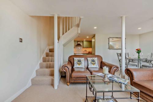 a living room with leather furniture and a staircase at The Old School House in Stow on the Wold