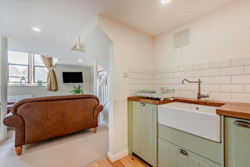 a kitchen with a sink and a couch in it at The Old School House in Stow on the Wold