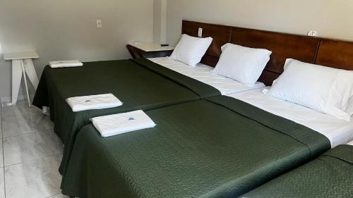 a bedroom with two beds with green sheets and white pillows at Pousada Mar & Sol in Tutóia