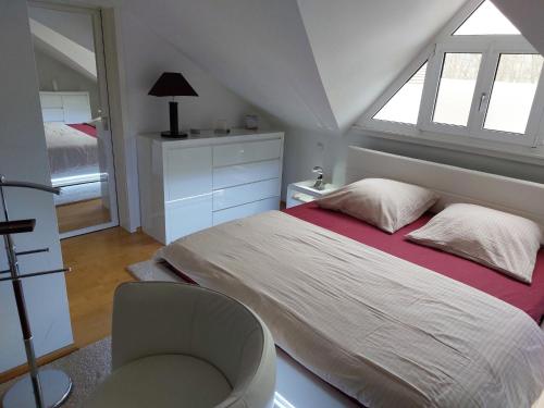 ein Schlafzimmer mit einem Bett, einem Stuhl und einem Fenster in der Unterkunft Ferienwohnung DG in Altenkunstadt