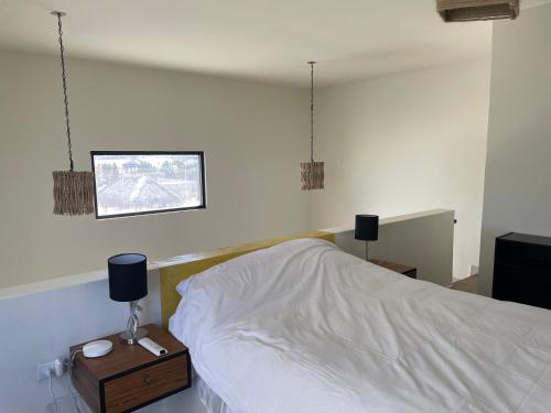 a bedroom with a bed with white sheets and a night stand at Chakana Lofts in El Pescadero