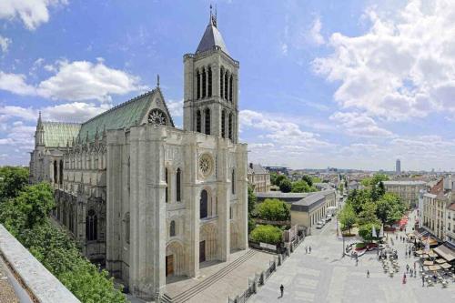 a large cathedral with a clock tower in a city at 2 pièces Metro 13 Porte de Paris - Stade de France in Saint-Denis