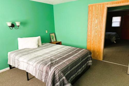Kadoka的住宿－Love Hotels Badlands National Park at Kadoka SD，一间卧室设有一张床和绿色的墙壁