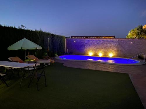 een achtertuin met een zwembad met tafels en een parasol bij Casa Aries - Villa con piscina privada in Linares