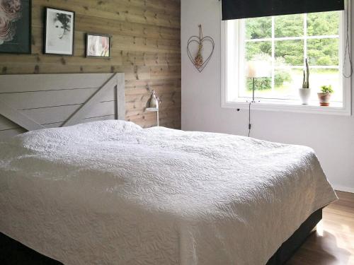 1 dormitorio con cama blanca y ventana en Holiday home Gunnarskog II, en Gunnarskog