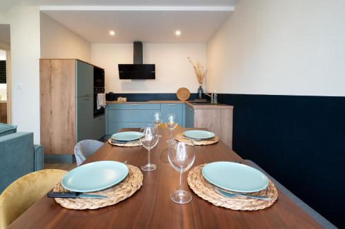 - une table à manger avec des assiettes et des verres à vin dans l'établissement Résidence St Marc - L'Art Déco - Centre ville, à Quimper