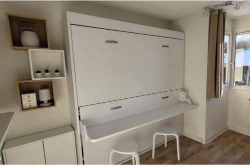 a white refrigerator in a room with two stools at Appartement 20m², tout confort, entièrement rénové in Prémanon