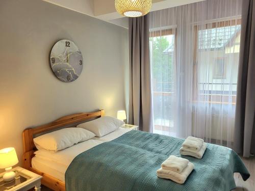 a bedroom with a bed and a clock on the wall at Apartament ORKAN przy Krupówkach in Zakopane