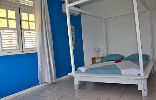 a bedroom with a white canopy bed with blue walls at Domaine Macabou in Le Vauclin