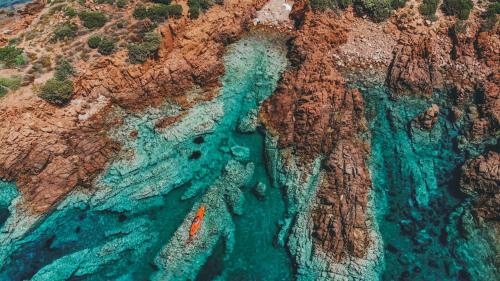 an aerial view of a cliff with a boat in the water at Hotel Marinedda Thalasso & Spa in Isola Rossa
