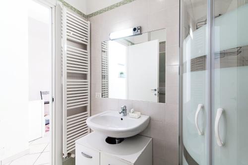 a white bathroom with a sink and a mirror at JOIVY Al Duomo guest house in Como