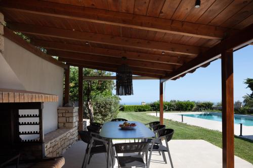 un patio con una mesa azul y sillas bajo una pérgola de madera en Malvasia Villa, en Skouloúfia