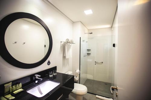a bathroom with a sink and a shower with a mirror at Transamerica Executive Maringá in Maringá
