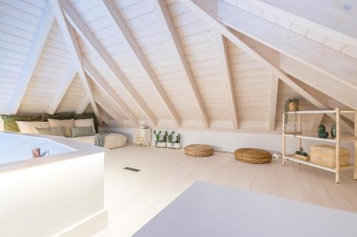 LODO Suits Ala - Studio mezanino by HD في فارو: غرفة علوية بسقف خشبي مع عوارض