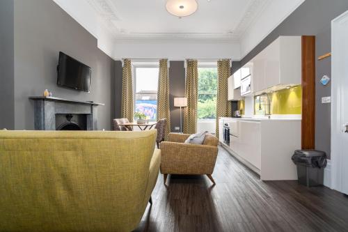a living room with a yellow couch and a kitchen at Charlotte Rise - Urban Apartments in Bristol
