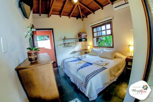 a bedroom with a large bed and a window at Pousada Manga Rosa in Ilhabela
