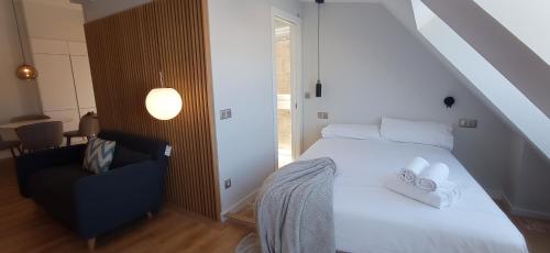 una camera con un letto bianco e una sedia di Príncipe Boutique apartments a Vigo