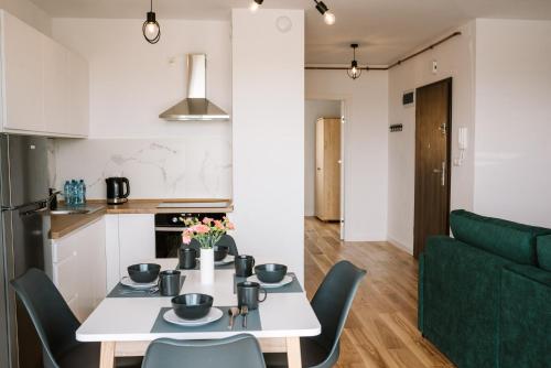 a kitchen and living room with a white table and chairs at Apartamenty DIAGO in Łeba