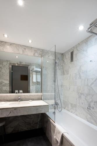 a bathroom with a tub and a sink and a shower at Catalonia Albeniz in Barcelona