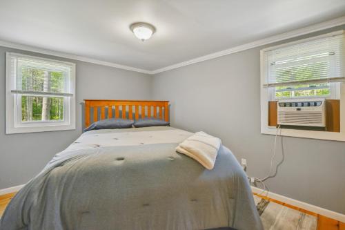 een slaapkamer met een bed en 2 ramen bij Brantingham Cabin with Porch and Grill On 5 Acres! in Glenfield