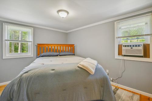 a bedroom with a bed and two windows at Brantingham Cabin with Porch and Grill On 5 Acres! in Glenfield