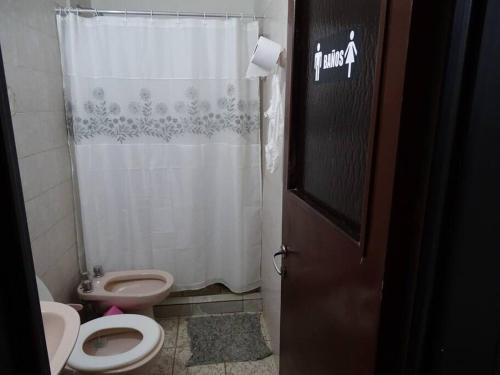 Un baño con inodoro y cortina de ducha. en Hostel, LA LULA, en Vinchina