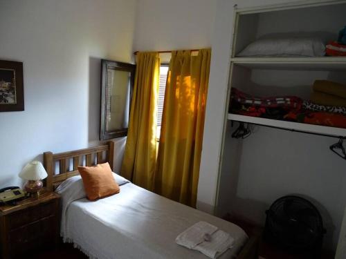 1 dormitorio con cama y cortina amarilla en Hostel, LA LULA, en Vinchina