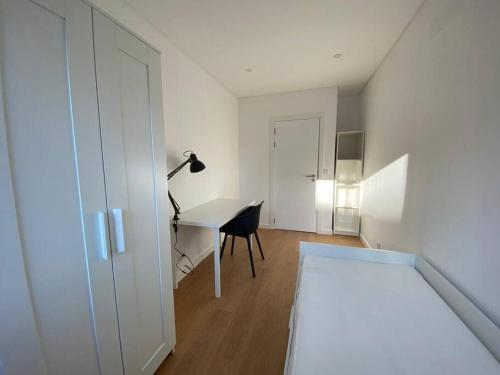 a white room with a desk and a table with a lamp at Carcavelos Beach Five Guests apartment in Oeiras