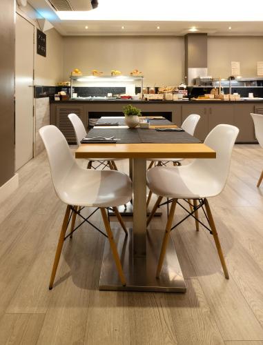 a dining room with a table and white chairs at Catalonia Albeniz in Barcelona