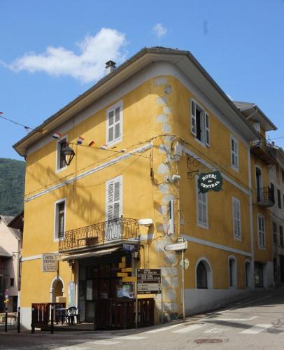 un bâtiment jaune avec un balcon dans une rue dans l'établissement Hotel Central, à Saint-Pierre-dʼAlbigny