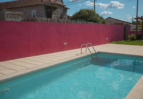 a swimming pool in front of a red wall at Casa das Tias in Baltar