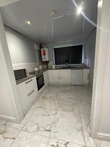 a kitchen with white cabinets and a marble floor at Lumiere luxury apartment 
