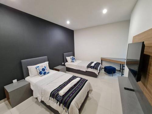 een slaapkamer met 2 bedden en een bureau. bij Lovely Kozi Square comfort Studio Home 2A in Kuching
