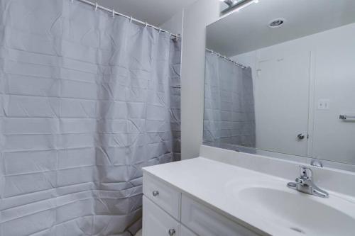 La salle de bains blanche est pourvue d'un lavabo et d'un miroir. dans l'établissement Modern & Spacious 2BR + Den Condo @Crystal City, à Arlington