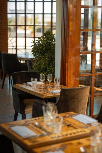 a restaurant with wooden tables and chairs with wine glasses at Ermitage de l'Oasis & Spa - Cannes Mandelieu in Mandelieu-la-Napoule