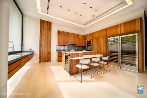 a kitchen with wooden cabinets and a island with bar stools at Sunny Vacation Villa No 31 in Bonao
