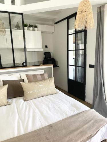 - une chambre avec un grand lit blanc et des fenêtres dans l'établissement Bastide Magdaleyna Mougins, à Mougins