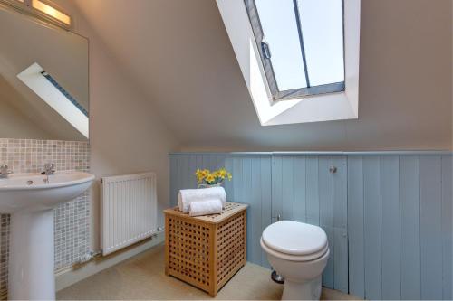 een badkamer met een toilet, een wastafel en een dakraam bij Riding Stable, Rookery Farm in West Beckham