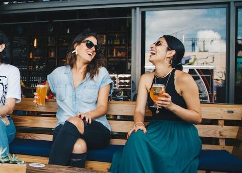two women sitting on a bench with drinks at Hotel Jeet Paradise in Phaltan