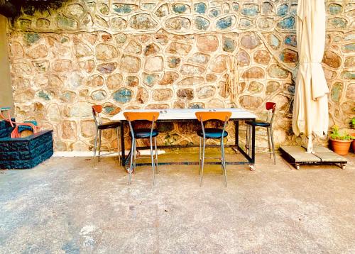 a table and three chairs in front of a stone wall at De&Ne apart 1 in Rize