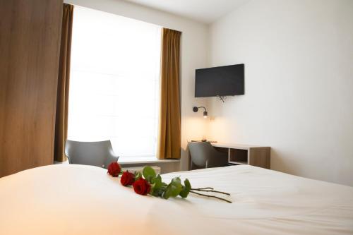 a bedroom with a white bed with roses on it at Alfa Inn in Blankenberge