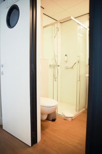 a bathroom with a toilet and a glass shower at Alfa Inn in Blankenberge