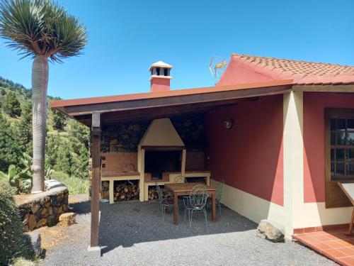 a house with a table and a palm tree at Casa Los Calderos in Villa de Mazo